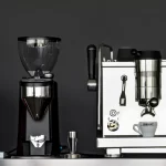 Rocket Espresso home coffee sitting besides a coffee grinder, coffee tamper, milk jug and decorative ornaments