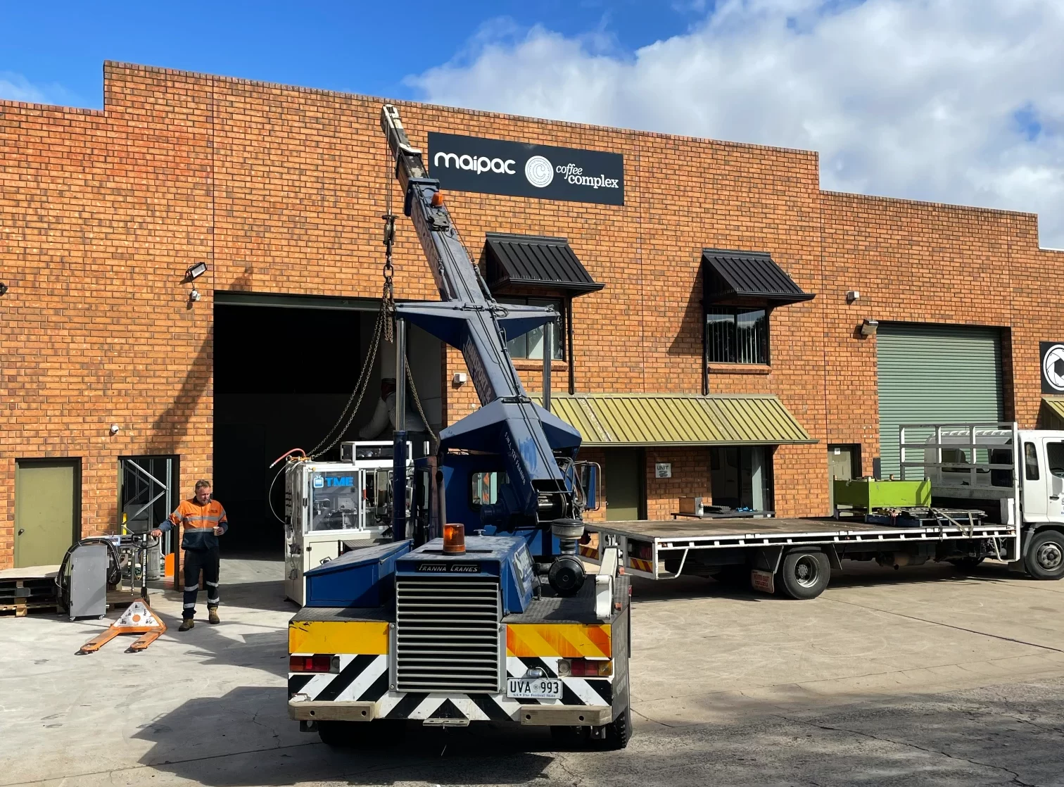 Small crane preparing to lift up a piece of coffee equipment infront of the Maipac coffee pod warehouse in Adelaide